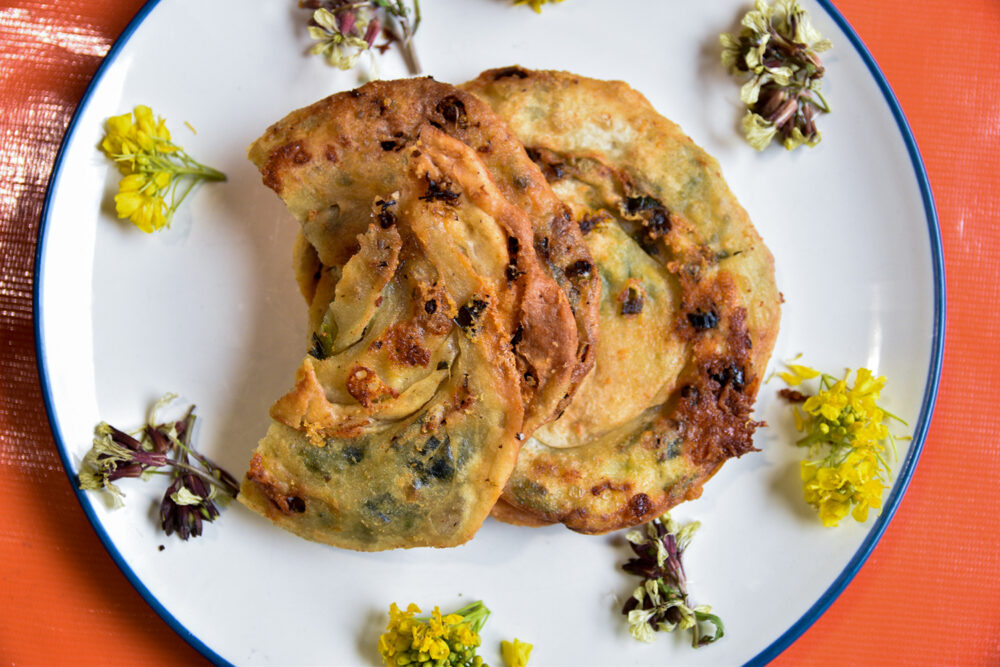 Plate with crispy sausage pancakes, edible flowers border the plate