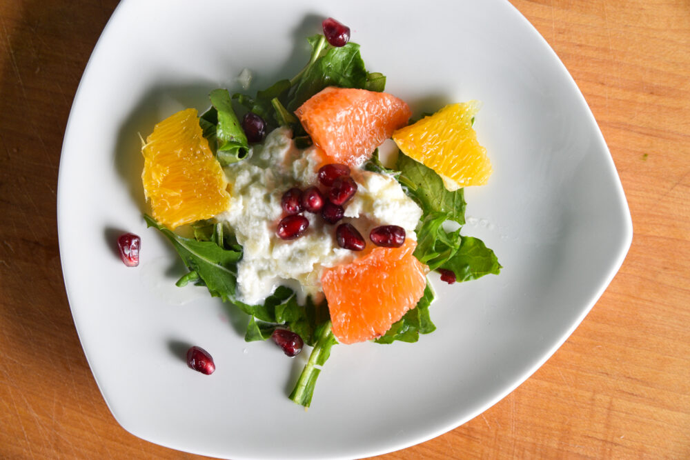 Sweet Straciatella and Fruit Salad, served on a white dish on a wooden board