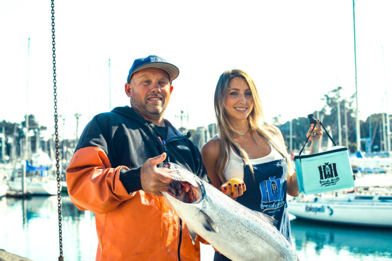 Hans and Heidi of H&H Fresh Fish Co. hold a fish on the waterfront