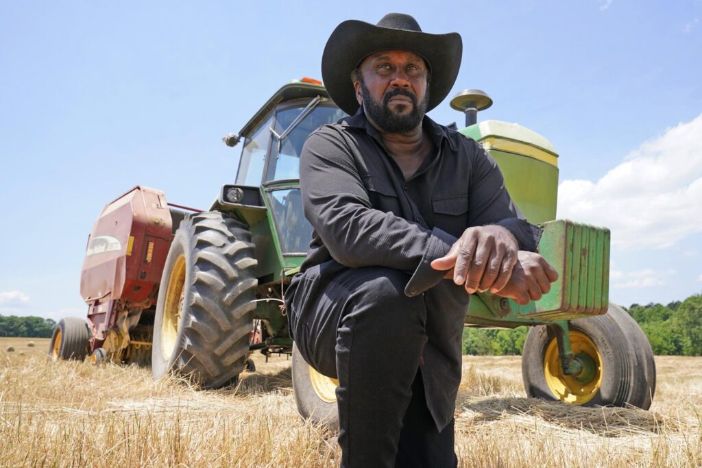 Picture of John Boyd kneeling in front of a tractor