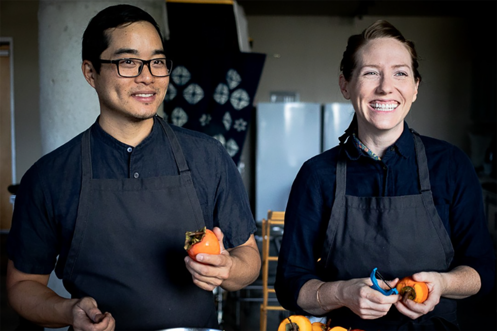 Photo of two people, each holding a persimmon.