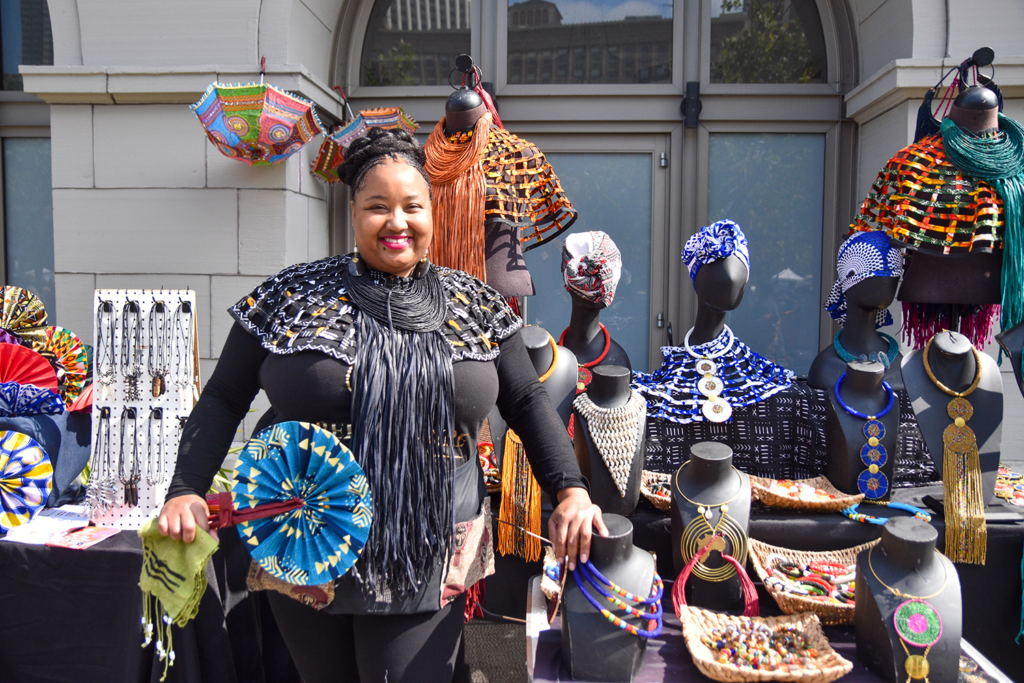 Nicole Williams poses in front of Belle Noire's stand at Foodwise and In The Black's Pop-Ups on the Plaza Black Creators Craft Market